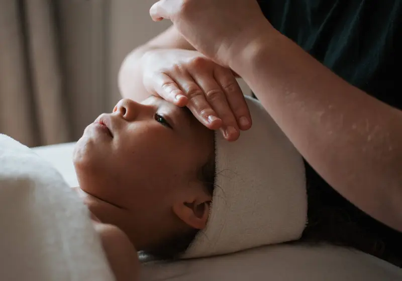 Un enfant allongé reçoit un massage du visage