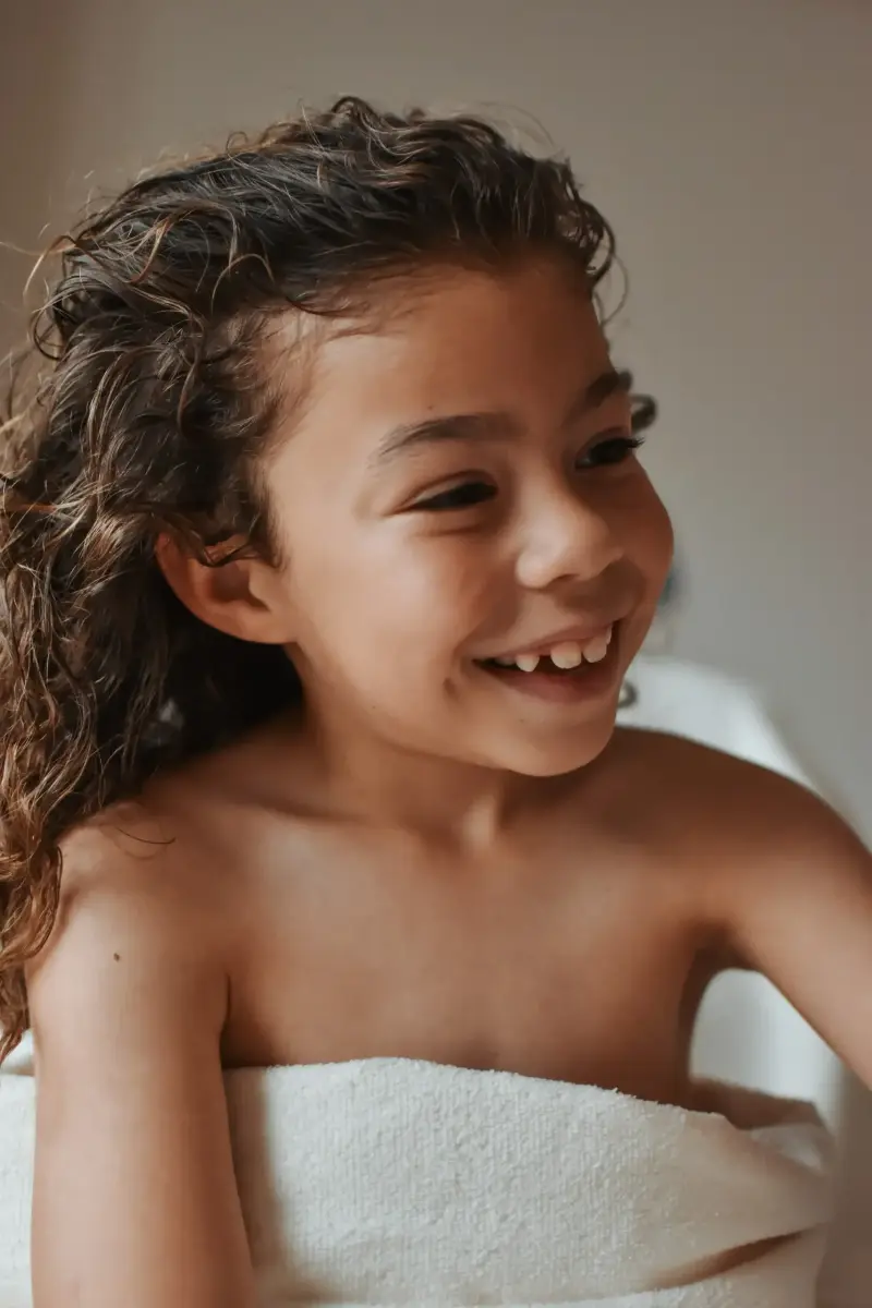 Une petite fille rieuse enveloppée dans une serviette après son massage