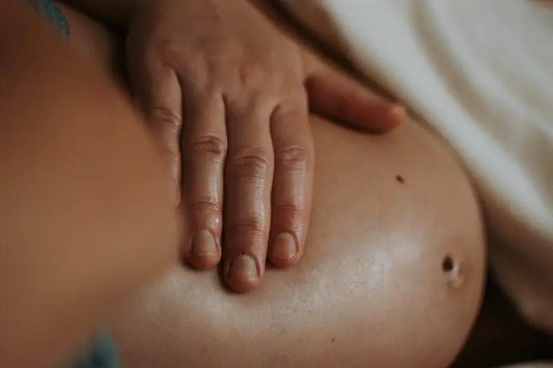Les mains de la praticienne sur le ventre arrondi d'une future maman